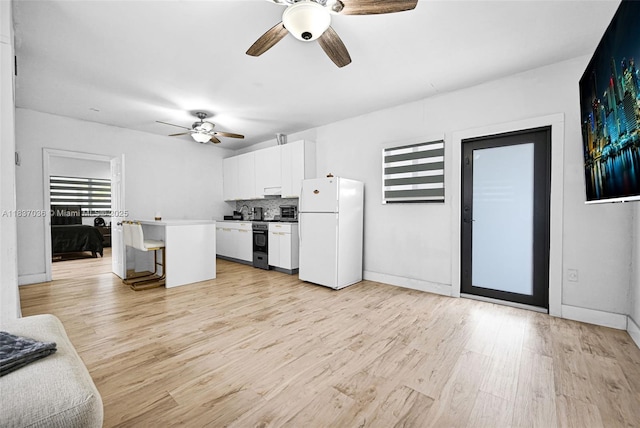 11055 NW 59th Ct, Hialeah, FL 33012 - kitchen featuring white appliances, ceiling fan, a breakfast bar, light wood-style flooring, and white cabinetry