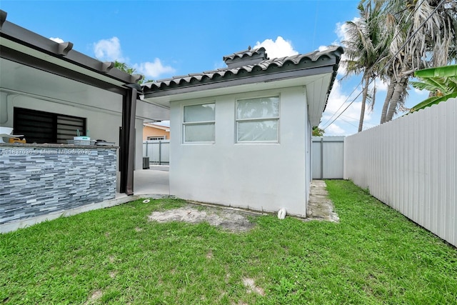11055 NW 59th Ct, Hialeah, FL 33012 - view of side of home with a fenced backyard, an outdoor kitchen, a tiled roof, and stucco siding