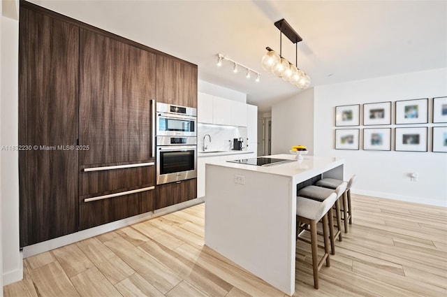 851 NE 1st Ave Unit 2809, Miami, FL 33132 - kitchen featuring black electric cooktop, a kitchen bar, light countertops, modern cabinets, and double oven