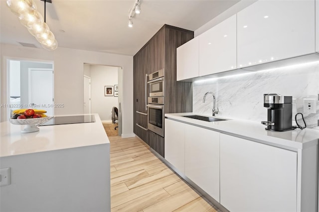 851 NE 1st Ave Unit 2809, Miami, FL 33132 - kitchen featuring decorative backsplash, white cabinets, black electric stovetop, and light wood-style floors