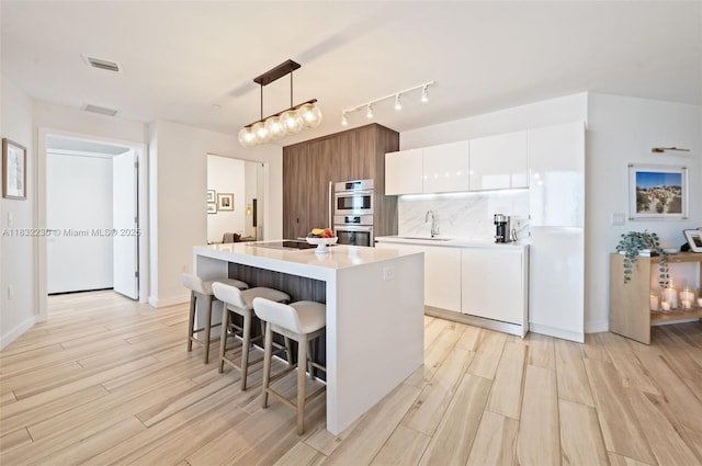 851 NE 1st Ave Unit 2809, Miami, FL 33132 - kitchen with stainless steel double oven, light wood finished floors, modern cabinets, and white cabinetry