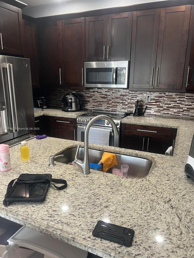 4301 SW 160th Ave Unit 215, Miramar, FL 33027 - kitchen featuring stainless steel appliances, backsplash, light stone countertops, and dark brown cabinets