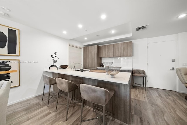 801 S Miami Ave Unit 1210, Miami, FL 33130 - kitchen with a breakfast bar, wood finished floors, a peninsula, light countertops, and recessed lighting