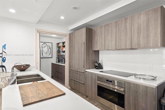 801 S Miami Ave Unit 1210, Miami, FL 33130 - kitchen with stainless steel oven, black electric cooktop, modern cabinets, light countertops, and recessed lighting