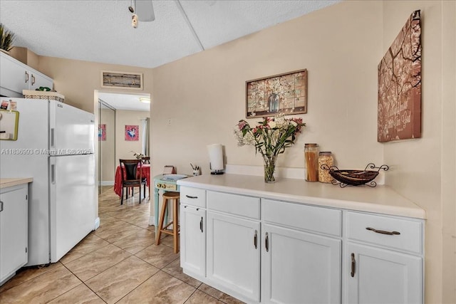 6555 W Broward Blvd Unit 300, Plantation, FL 33317 - kitchen with freestanding refrigerator, white cabinets, light countertops, light tile patterned flooring, and a textured ceiling