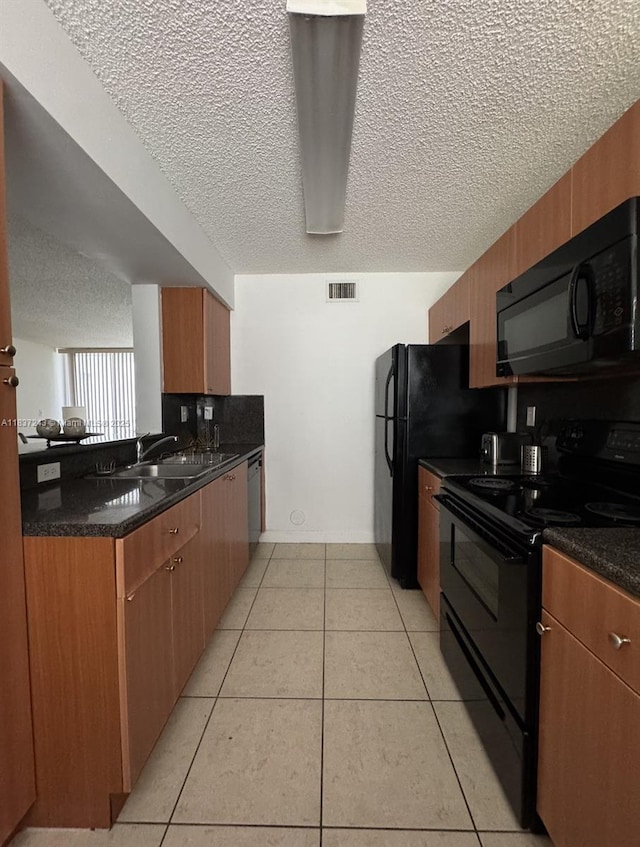 9755 NW 48th Ter Unit 321, Doral, FL 33178 - kitchen featuring black appliances, a textured ceiling, light tile patterned flooring, and brown cabinetry