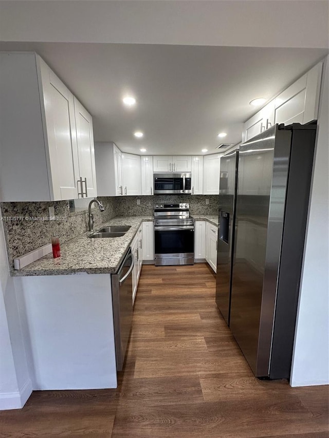 6547 SW 35th St, Miami, FL 33155 - kitchen with appliances with stainless steel finishes, light stone counters, tasteful backsplash, white cabinets, and dark wood finished floors