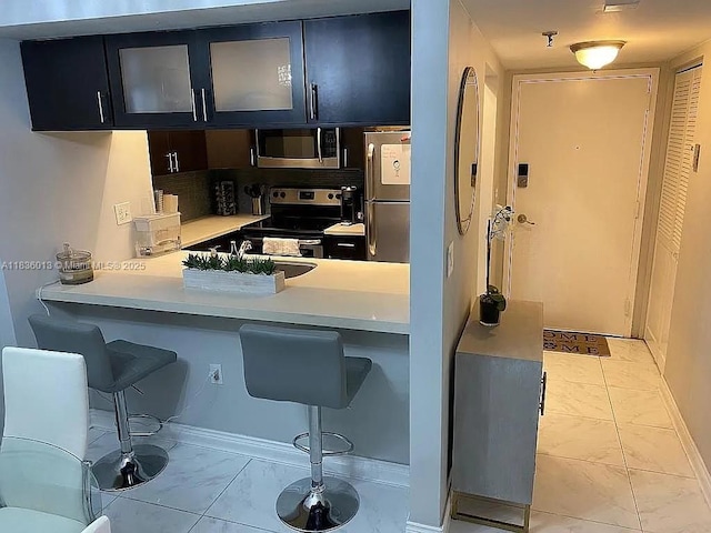 800 N Miami Ave Unit E-707, Miami, FL 33136 - kitchen with appliances with stainless steel finishes, light marble finish flooring, a breakfast bar, and glass insert cabinets