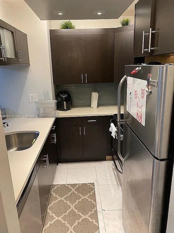 800 N Miami Ave Unit E-707, Miami, FL 33136 - kitchen with freestanding refrigerator, light countertops, tasteful backsplash, range, and dark brown cabinetry