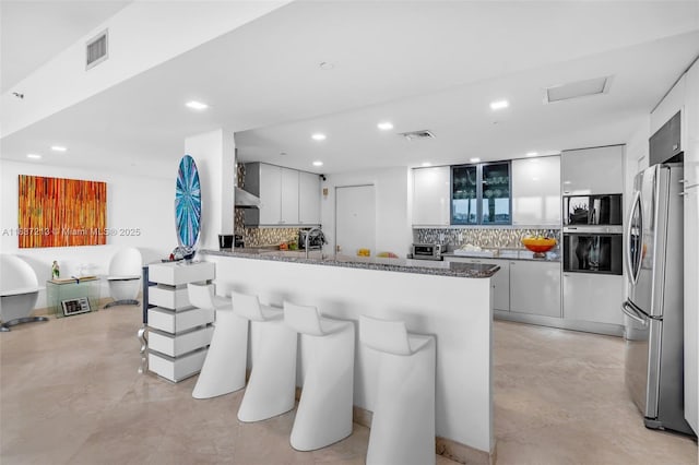 1643 Brickell Ave Unit 1406, Miami, FL 33129 - kitchen with appliances with stainless steel finishes, a peninsula, decorative backsplash, recessed lighting, and a breakfast bar