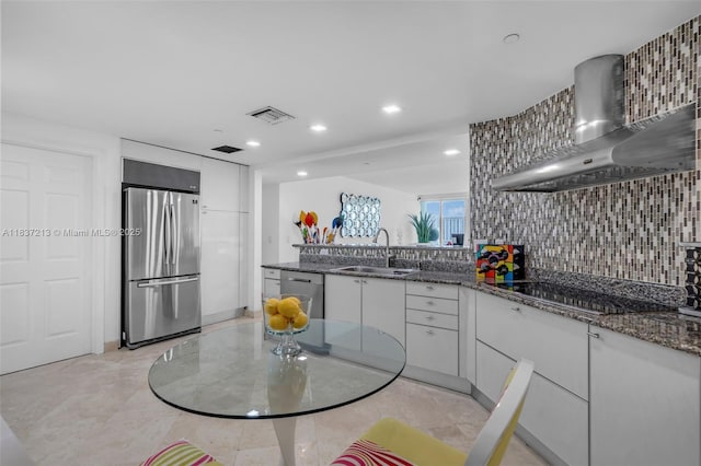 1643 Brickell Ave Unit 1406, Miami, FL 33129 - kitchen featuring stainless steel appliances, wall chimney exhaust hood, white cabinets, dark stone countertops, and recessed lighting