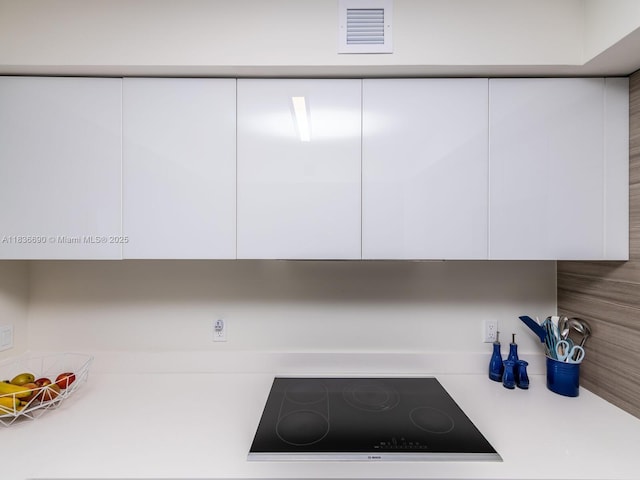 300 Sunny Isles Blvd Unit 5-1605, Sunny Isles Beach, FL 33160 - kitchen view of black electric cooktop, white cabinets, and light countertops