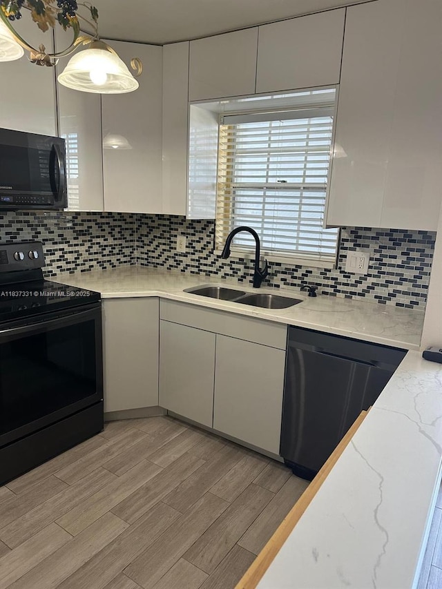 661 N University Dr Unit 1-201, Pembroke Pines, FL 33024 - kitchen with black appliances, white cabinetry, backsplash, light wood-type flooring, and modern cabinets
