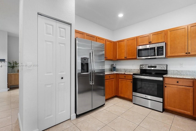 4326 Braxton Ave, West Palm Beach, FL 33417 - kitchen with stainless steel appliances, light tile patterned floors, brown cabinets, and light stone countertops