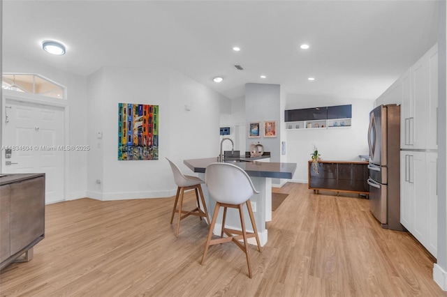 16410 Sapphire Bnd, Weston, FL 33331 - kitchen with freestanding refrigerator, a breakfast bar, light wood-style floors, lofted ceiling, and white cabinetry