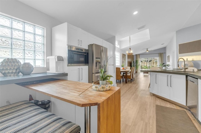 16410 Sapphire Bnd, Weston, FL 33331 - kitchen featuring appliances with stainless steel finishes, white cabinetry, wood counters, light wood-style flooring, and a kitchen breakfast bar