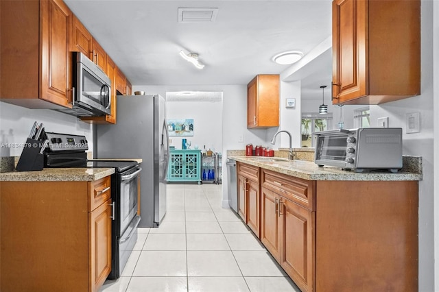 4803 NW 47th Ter, Tamarac, FL 33319 - kitchen with appliances with stainless steel finishes, light tile patterned flooring, brown cabinetry, and light countertops