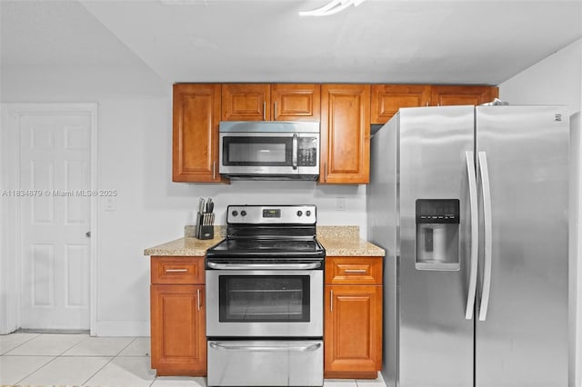 4803 NW 47th Ter, Tamarac, FL 33319 - kitchen with appliances with stainless steel finishes, brown cabinets, light tile patterned floors, and light stone countertops