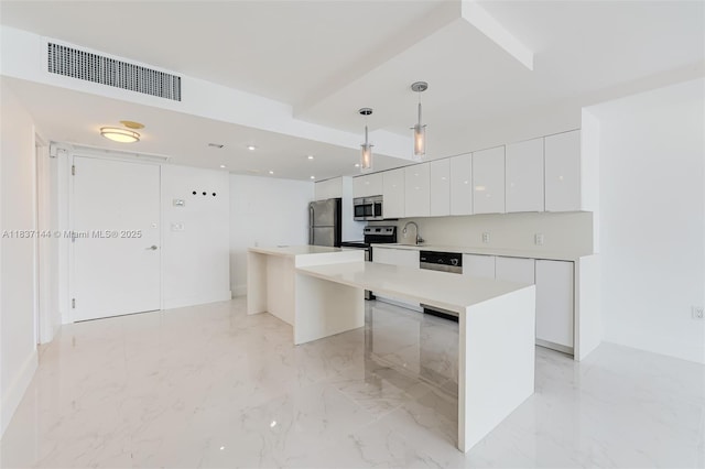 5701 Collins Ave Unit 1611, Miami Beach, FL 33140 - kitchen featuring modern cabinets, appliances with stainless steel finishes, white cabinetry, decorative light fixtures, and a kitchen island