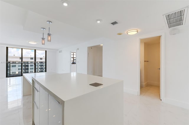 5701 Collins Ave Unit 1611, Miami Beach, FL 33140 - kitchen with modern cabinets, decorative light fixtures, a kitchen island, light countertops, and light marble finish floors