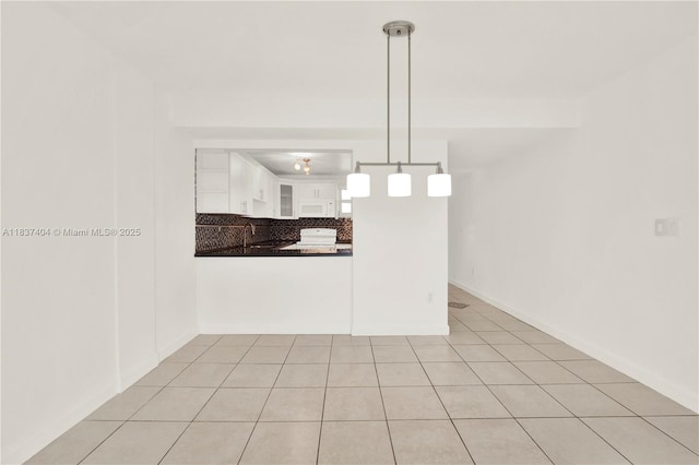 1990 W 56th St Unit 1407, Hialeah, FL 33012 - kitchen with dark countertops, white cabinets, white microwave, decorative light fixtures, and glass insert cabinets
