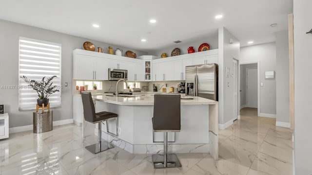 16204 SW 18th Pl, Miramar, FL 33027 - kitchen featuring stainless steel appliances, light countertops, a kitchen breakfast bar, light marble finish flooring, and white cabinetry
