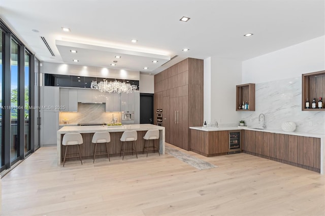416 NW 24th St, Wilton Manors, FL 33311 - kitchen with modern cabinets, decorative backsplash, light wood finished floors, beverage cooler, and recessed lighting