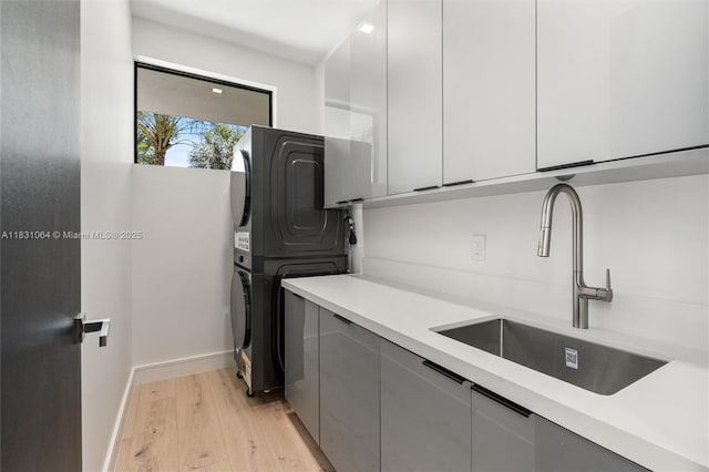 416 NW 24th St, Wilton Manors, FL 33311 - kitchen with stacked washer / dryer, light wood-style flooring, light countertops, white cabinets, and modern cabinets