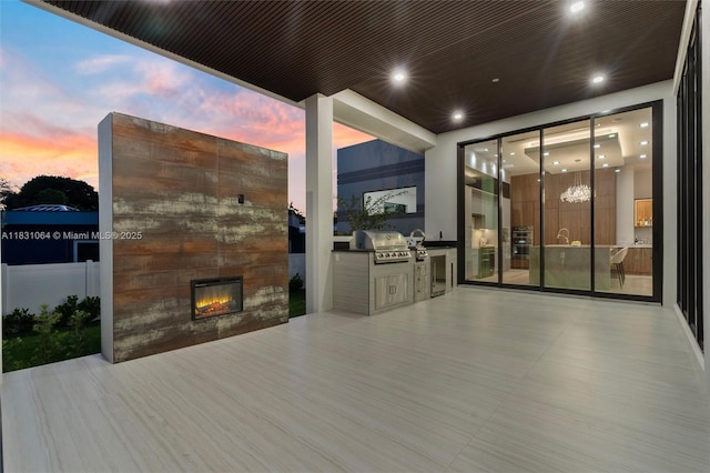 416 NW 24th St, Wilton Manors, FL 33311 - patio terrace at dusk with a glass covered fireplace and an outdoor kitchen