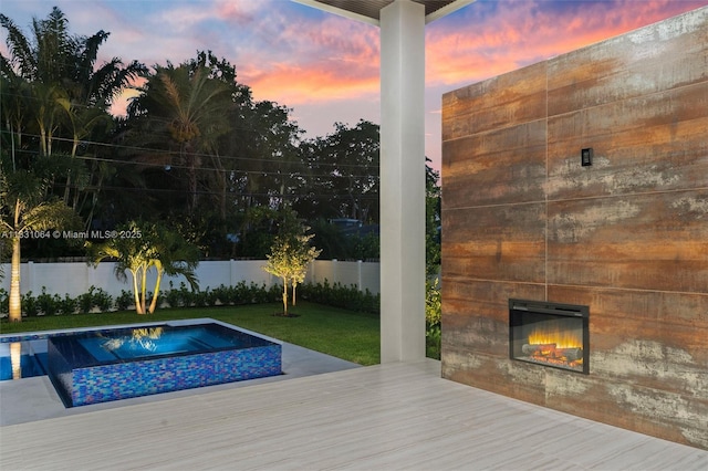 416 NW 24th St, Wilton Manors, FL 33311 - pool at dusk with a glass covered fireplace, a fenced backyard, and a deck