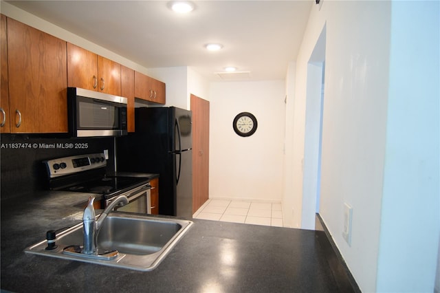 20825 NE 8th Ct Unit 203-19, Miami, FL 33179 - kitchen featuring stainless steel appliances, brown cabinets, light tile patterned floors, and dark countertops
