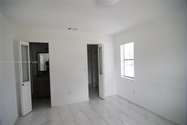 20825 NE 8th Ct Unit 203-19, Miami, FL 33179 - unfurnished bedroom featuring light marble finish flooring, a spacious closet, and a textured ceiling