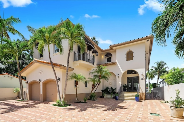 66 S Hibiscus Dr, Miami Beach, FL 33139 - mediterranean / spanish-style house with a balcony, a garage, french doors, decorative driveway, and stucco siding