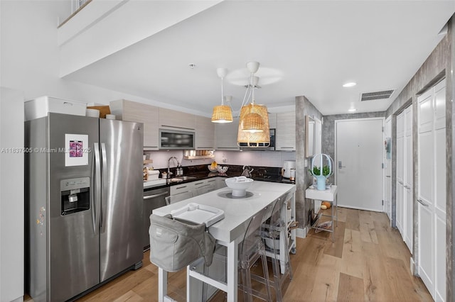 244 Biscayne Blvd Unit 446, Miami, FL 33132 - kitchen featuring stainless steel appliances, light wood finished floors, modern cabinets, and hanging light fixtures