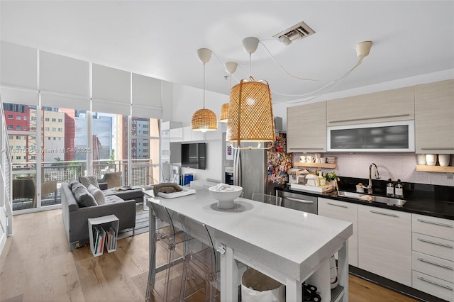 244 Biscayne Blvd Unit 446, Miami, FL 33132 - kitchen featuring modern cabinets, appliances with stainless steel finishes, light wood-type flooring, open floor plan, and a kitchen island