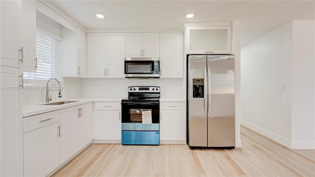 2820 NW 95th St, Miami, FL 33147 - kitchen featuring appliances with stainless steel finishes, light wood finished floors, white cabinets, light countertops, and decorative backsplash