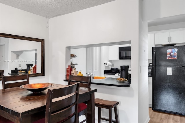 9730 Hammocks Blvd Unit 201-28, Miami, FL 33196 - kitchen featuring black appliances, white cabinetry, light wood finished floors, and a textured ceiling
