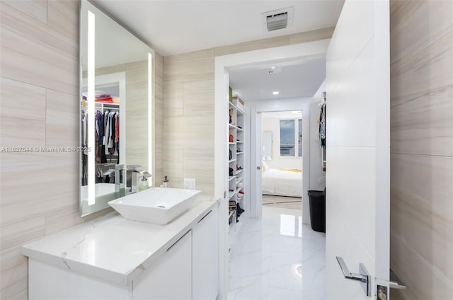 701 Brickell Key Blvd Unit 2011, Miami, FL 33131 - ensuite bathroom featuring tile walls, vanity, a spacious closet, and marble tiled floors