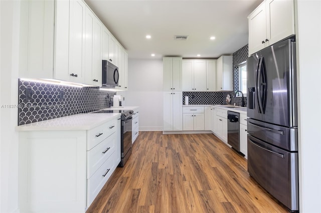 121 SE 7th St, Pompano Beach, FL 33060 - kitchen featuring black appliances, tasteful backsplash, light countertops, wood finished floors, and recessed lighting