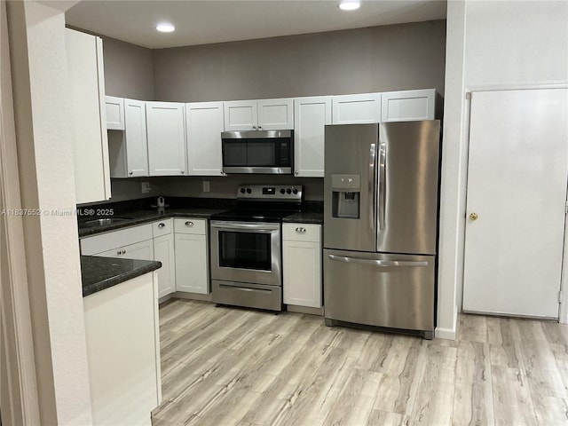 4603 Highgate Dr Unit C, Delray Beach, FL 33445 - kitchen with appliances with stainless steel finishes, dark countertops, light wood-type flooring, white cabinets, and recessed lighting