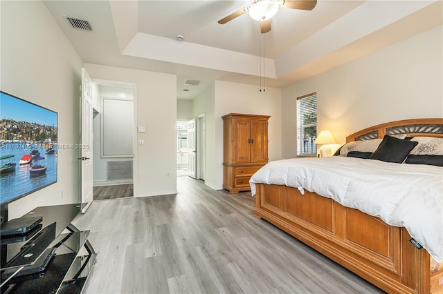 13850 NW 23rd St, Pembroke Pines, FL 33028 - bedroom with light wood-type flooring, a raised ceiling, connected bathroom, and a ceiling fan
