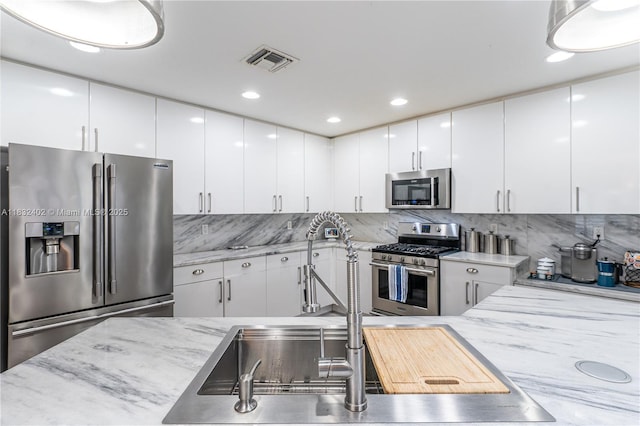 13850 NW 23rd St, Pembroke Pines, FL 33028 - kitchen with stainless steel appliances, white cabinets, tasteful backsplash, light stone counters, and recessed lighting