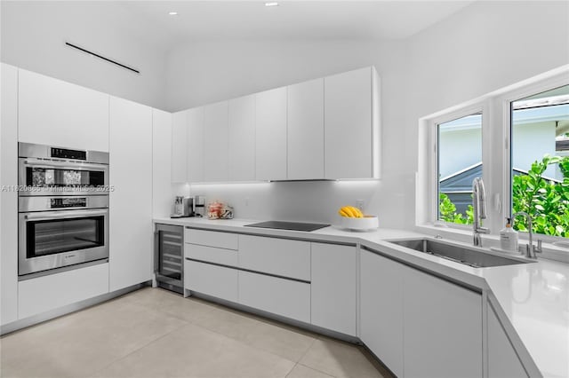 9033 Emerson Ave, Surfside, FL 33154 - kitchen featuring beverage cooler, stainless steel double oven, light countertops, white cabinetry, and lofted ceiling