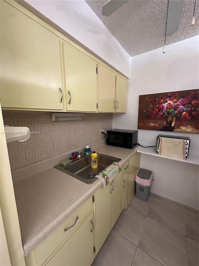 920 SW 11th Ave Unit 12A, Hallandale Beach, FL 33009 - kitchen with black microwave, cream cabinets, light countertops, light tile patterned floors, and a textured ceiling