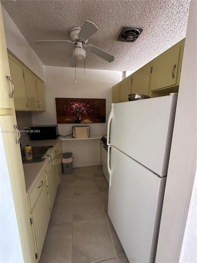 920 SW 11th Ave Unit 12A, Hallandale Beach, FL 33009 - kitchen featuring freestanding refrigerator, light tile patterned flooring, a textured ceiling, a ceiling fan, and cream cabinets