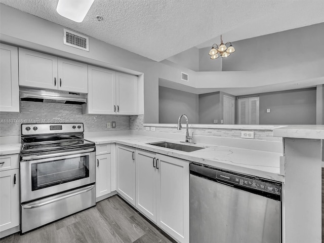 2071 Renaissance Blvd Unit 303, Miramar, FL 33025 - kitchen featuring stainless steel appliances, under cabinet range hood, a textured ceiling, light wood-style flooring, and a peninsula