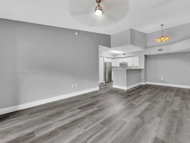 2071 Renaissance Blvd Unit 303, Miramar, FL 33025 - unfurnished living room featuring a chandelier, a textured ceiling, dark wood-type flooring, ceiling fan, and a towering ceiling