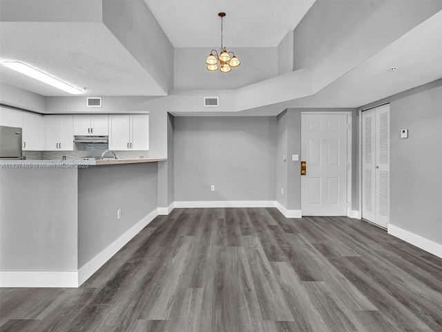2071 Renaissance Blvd Unit 303, Miramar, FL 33025 - kitchen featuring under cabinet range hood, white cabinetry, a chandelier, and dark wood-style flooring