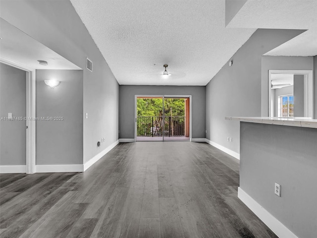 2071 Renaissance Blvd Unit 303, Miramar, FL 33025 - unfurnished living room featuring dark wood-style flooring, plenty of natural light, and a textured ceiling
