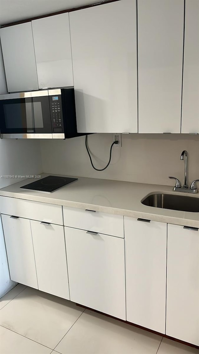 19201 Collins Ave Unit 330, Sunny Isles Beach, FL 33160 - kitchen with stainless steel microwave, black electric stovetop, light countertops, and white cabinets